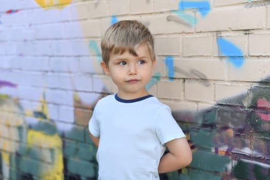 Boy with blue eyes near a colorful wall