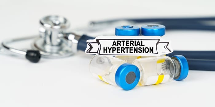 Medical concept. On the table there is a stethoscope, injections and a sign with the inscription - arterial hypertension