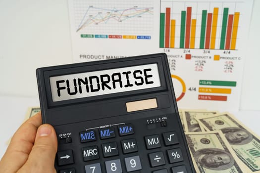 Business concept. On the table there are financial reports, dollars, in the hands of a calculator with the inscription - Fundraise