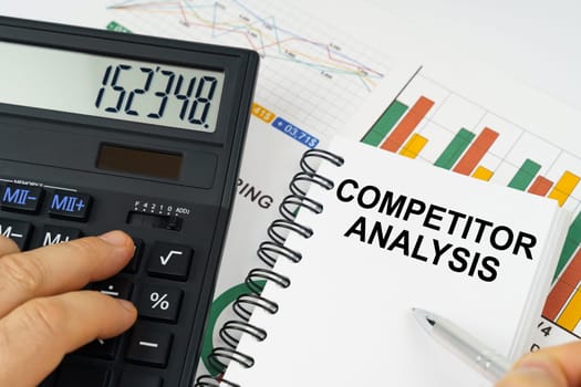 Business concept. On the table there is a calculator, reports with graphs and a notepad with the inscription - Competitor Analysis