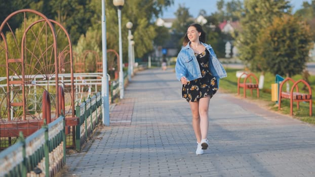 A cheerful girl walks along the city promenade