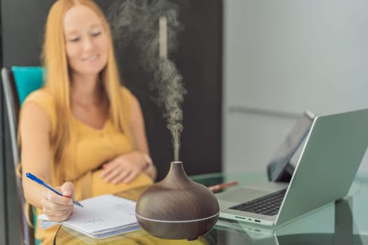 Expectant woman enhances work environment, using an aroma diffuser for a soothing atmosphere during pregnancy.