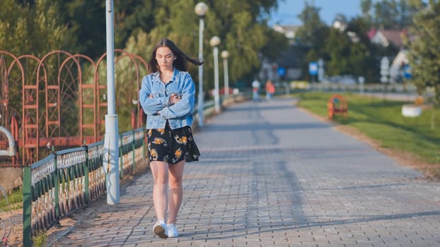 A lonely girl walks along the city's promenade