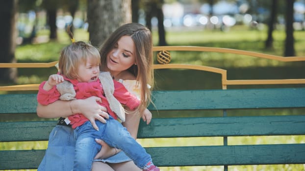 A mother soothes a crying baby in the park