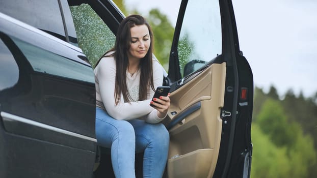 A girl is looking through her phone while sitting in her car
