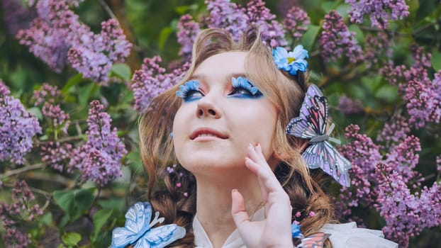 A young girl poses in lilac with a beautiful hairstyle of flowers and butterflies