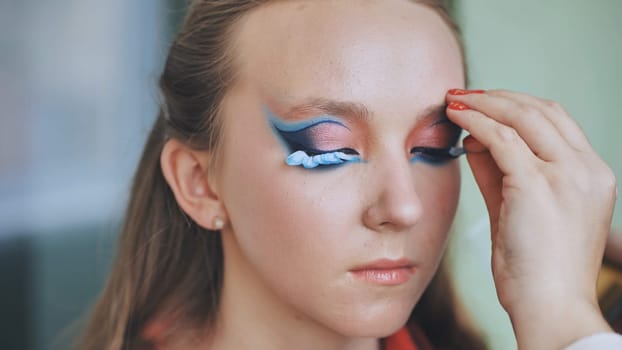 The makeup artist attaches flower petals to the lashes