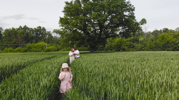 A young couple with their newborn baby in green wheat in a field