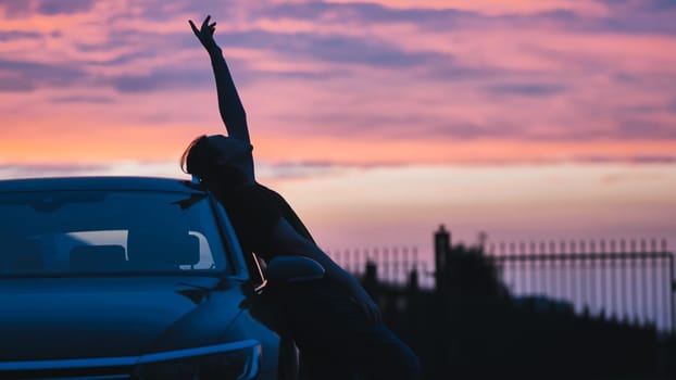 Silhouette of a young girl in front of her car at sunset