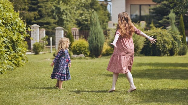 A mother and her daughter twirl in the garden outside the house