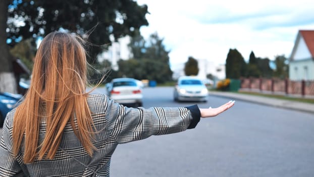 A girl is waving to a cab in the city
