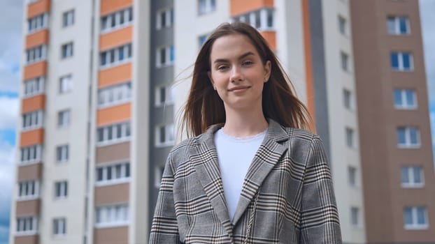 Portrait of a girl in front of a high-rise apartment building