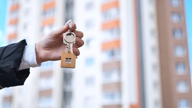 Girl holding keys to apartment against the backdrop of an apartment building