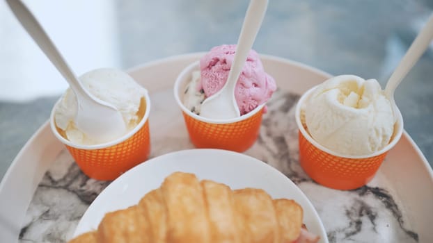 Ice cream and croissant with meat on the plate at the cafe