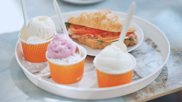 Ice cream and croissant with meat on the plate at the cafe