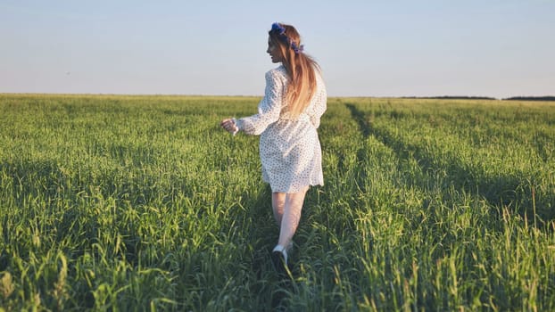 A young Ukrainian girl is running through a young wheat field