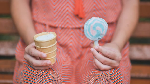 Teenage girl eating ice cream in the park on the bench. hands. Ice cream close-up