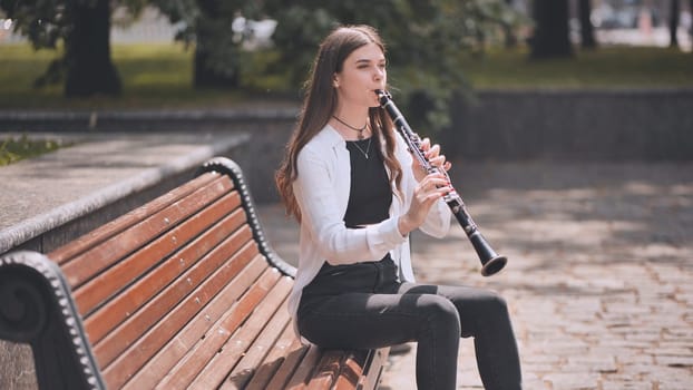 A girl plays the clarinet in the park