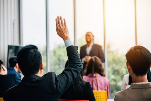 Active engagement during the seminar as attendees raise hands to ask questions emphasizing collaboration teamwork and knowledge-sharing.