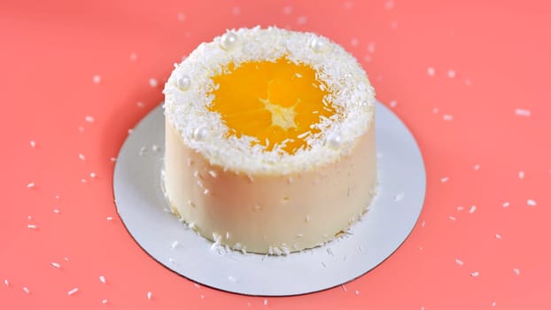 Cake with orange and coconut shavings spun on a pink background