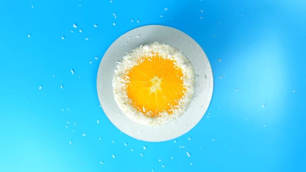 Cake with orange and coconut shavings spinning on a blue background