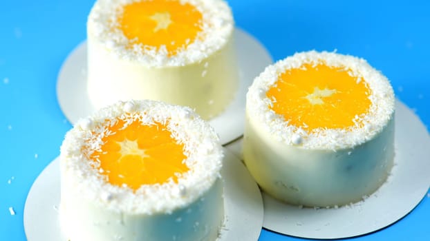 Small cakes with orange and coconut on a blue background