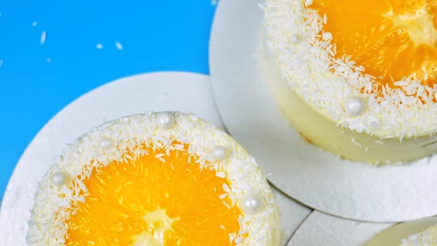 Small cakes with orange and coconut on a blue background