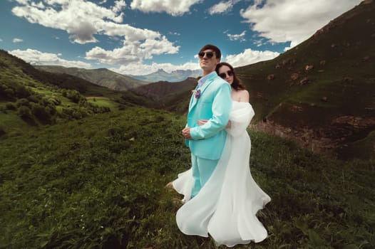 Beautiful wedding photo in the mountains, a wedding couple of newlyweds in love hugging against the backdrop of greenery and a cloudy sky.