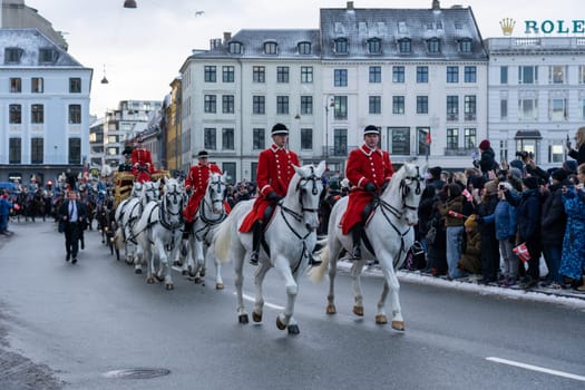 Copenhagen, Denmark - January 04, 2024: Queen Margrethe in her 24-carat golden coach is escorted by the Guard Hussar Regiment on the way from Christiansborg Palace to Amalienborg Palacce