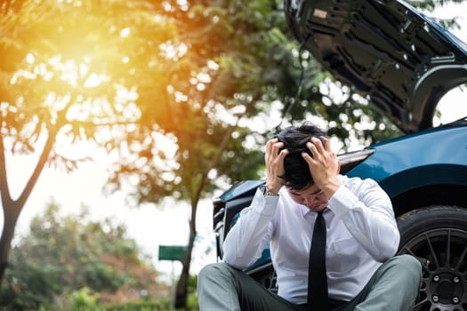 Young businessman calling for help with his broken down car on the side of a rural road. Concept of transportation problems and assistance.