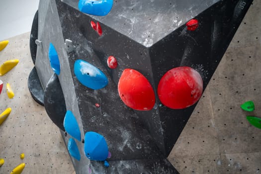 Closeup of climb wall with red and blue grips in contemporary gym. Indoor bouldering and climbing wall for training at sports center.