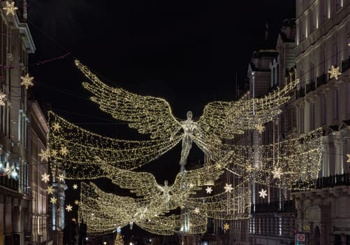 London, UK - Dec 25, 2023 - Flying angel Christmas decoration led lights display. Dramatic view of the traditional Christmas decoration lights hanging above Regent Street during dusk, The Spirit of Christmas, Light Festival in London, Space for text, Selective focus.
