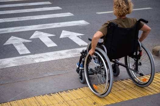 Rear view of an elderly woman on a wheelchair going to a pedestrian crossing