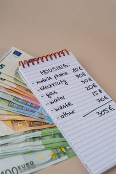 Euro cash money with notebook handwritten housing expenses. Counting bills for electricity, gas, water. Concept of Efficient Consumption and Economy. Spending habits