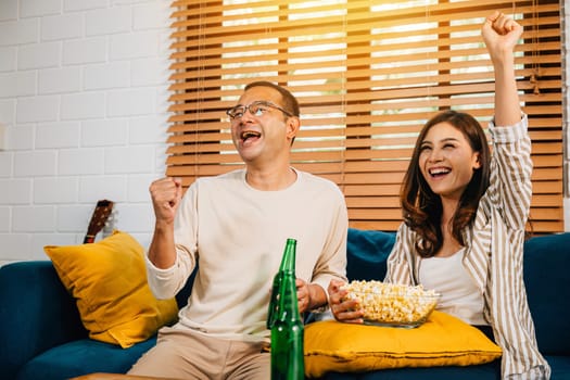 A jubilant Asian couple husband and wife cheer for a football goal during their leisure weekend creating an atmosphere of joy excitement and togetherness as dedicated sports enthusiasts.