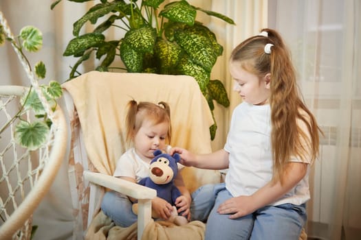 Happy time concept. Girls Sisters in chair and having fun. Female Preschooler and teenager playing and relaxing in room