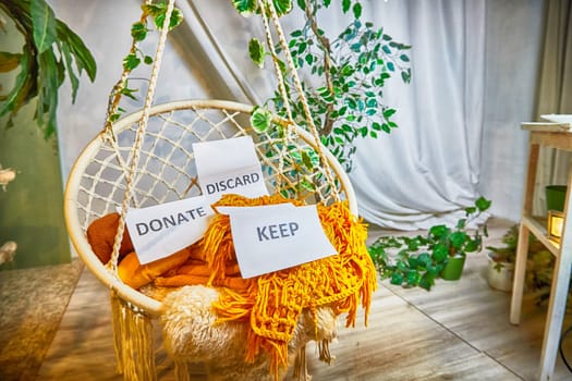 Signs with the words keep, donate, discard and fashion clothes folded in stacks in cozy room. The concept of cluttering and decluttering. Background