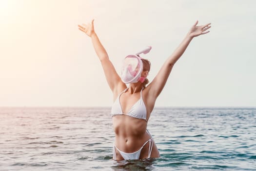 Young happy woman in white bikini put pink snorkeling mask on beach before swimming. girl having fun relaxing on beautiful beach. Beach lifestyle