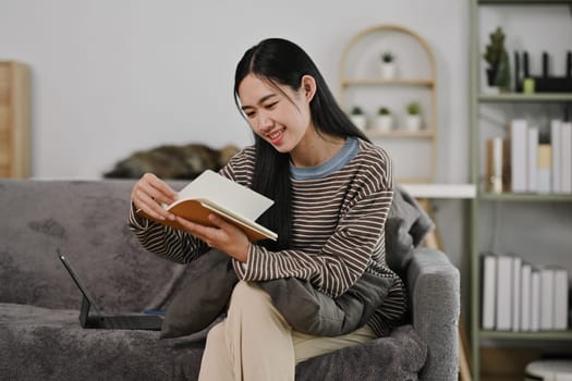 Attractive young woman reading book on couch at home. People, leisure and lifestyle concept.
