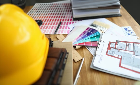 On table is apartment plan and protective helmet. Home renovation concept with comfort city apartment. Construction comfortable energy-efficient country houses. Development an exclusive project