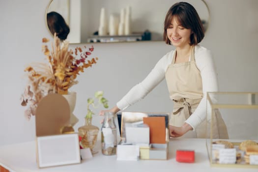 Female barista in apron standing at the counter in coffee shop and takes orders from client