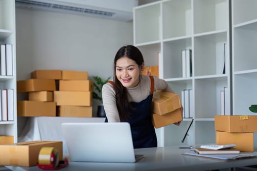 Startup SME small business entrepreneur SME or freelance Asian woman using a laptop with box, Young success Asian woman online marketing package box and delivery concept.