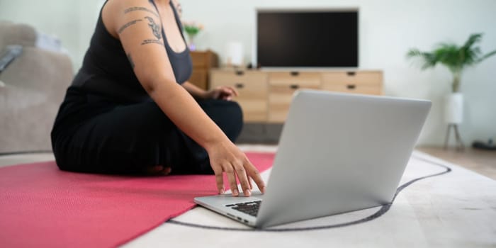 Women exercise on yoga mat and use laptops to watch workout clips. wellness home concept.