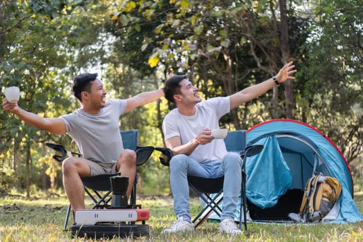 Asian LGBTQ couple drinking coffee in a romantic camping tent. LGBTQ couple drinking coffee in a camping tent, enjoying nature, forest, camping atmosphere, LGBTQ, gay, gay men..