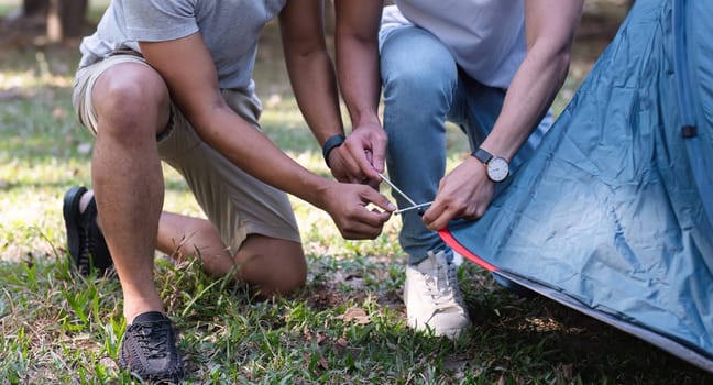 Asian LGBTQ couple camping together Set up a tent on the grass during the weekend.