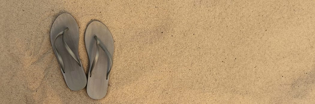 banner of light sandal or flip flops on the beach. golden sand. place for your text. top view. flat lay. concept of summer and vacation at sea