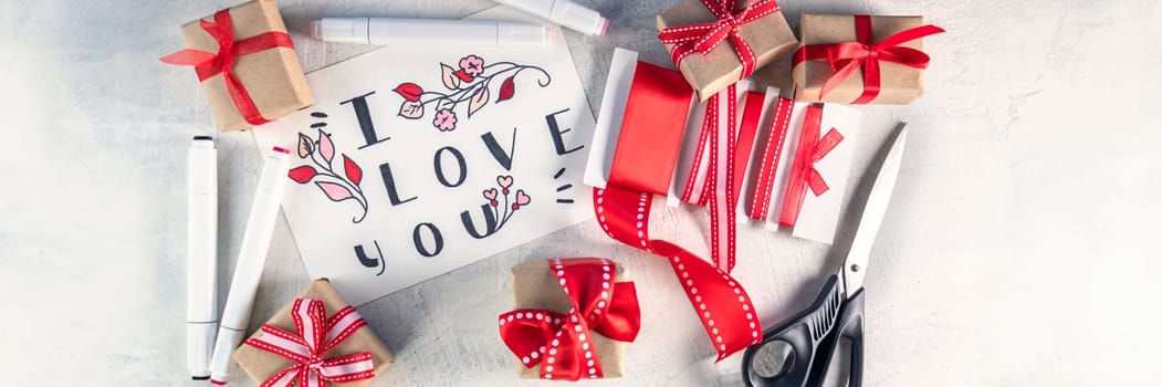 banner of red ribbons, gifts, scissors, markers next to valentine with words I love you . Preparation for Valentine's Day. Valentine's day concept. Flat lay. Top view