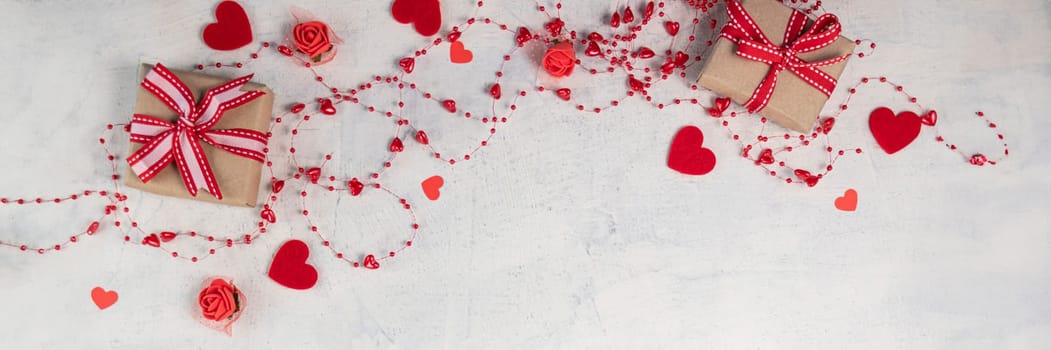 banner of two gifts with red ribbon on white textured background with red beads with hearts. background for valentine's day with space for your text. Soft focus. flat lay