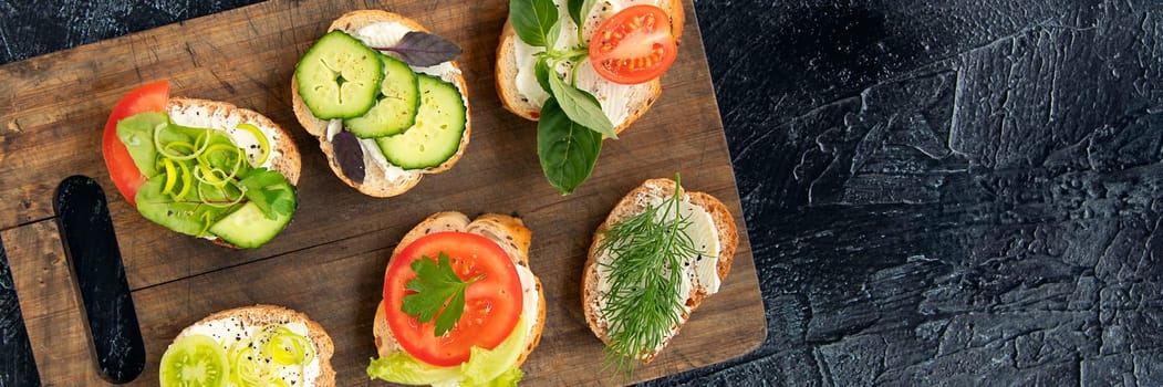 banner of six vegetable sandwiches with cream cheese, tomatoes, dill, cucumbers, leeks and basil. serving a vegetarian sandwiches for appetizers on cutting board. top view flat lay