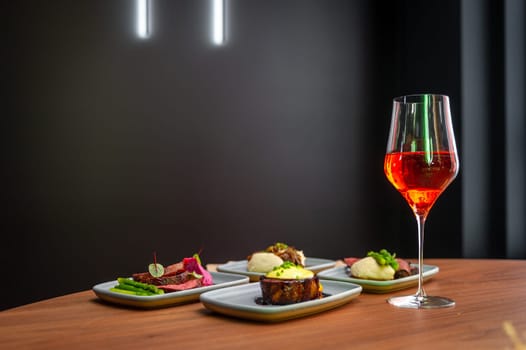 A set of dishes on a table in a restaurant with a glass of wine on a dark background, copy space. High quality photo.